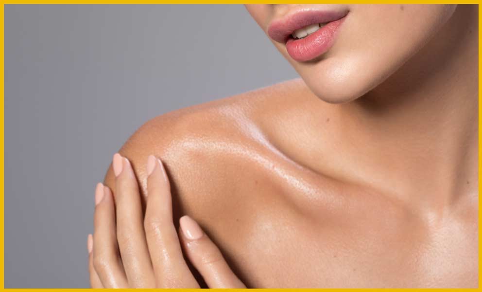 Close crop of a shoulder and collarbone photographed against a plain backdrop.
